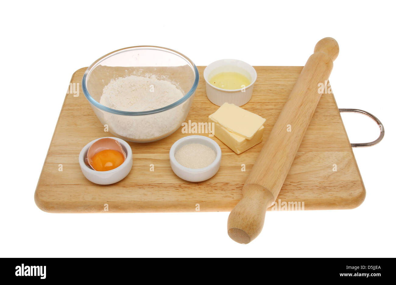 Ingredients for making pastry and a rolling pin on a wooden board isolated against white Stock Photo