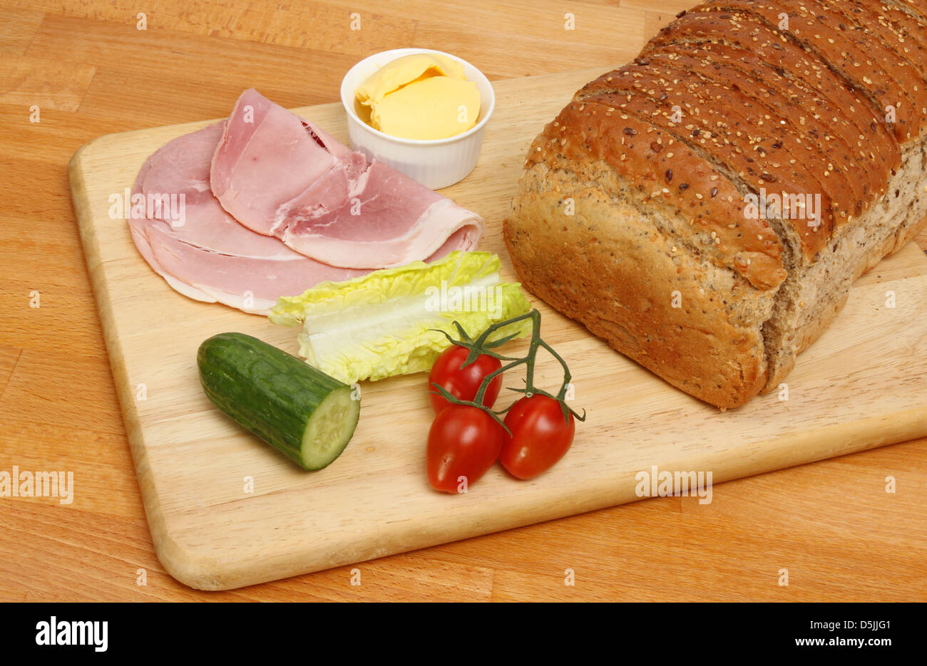 Wholemeal bread loaf and sandwich ingredients on aboard and worktop Stock Photo