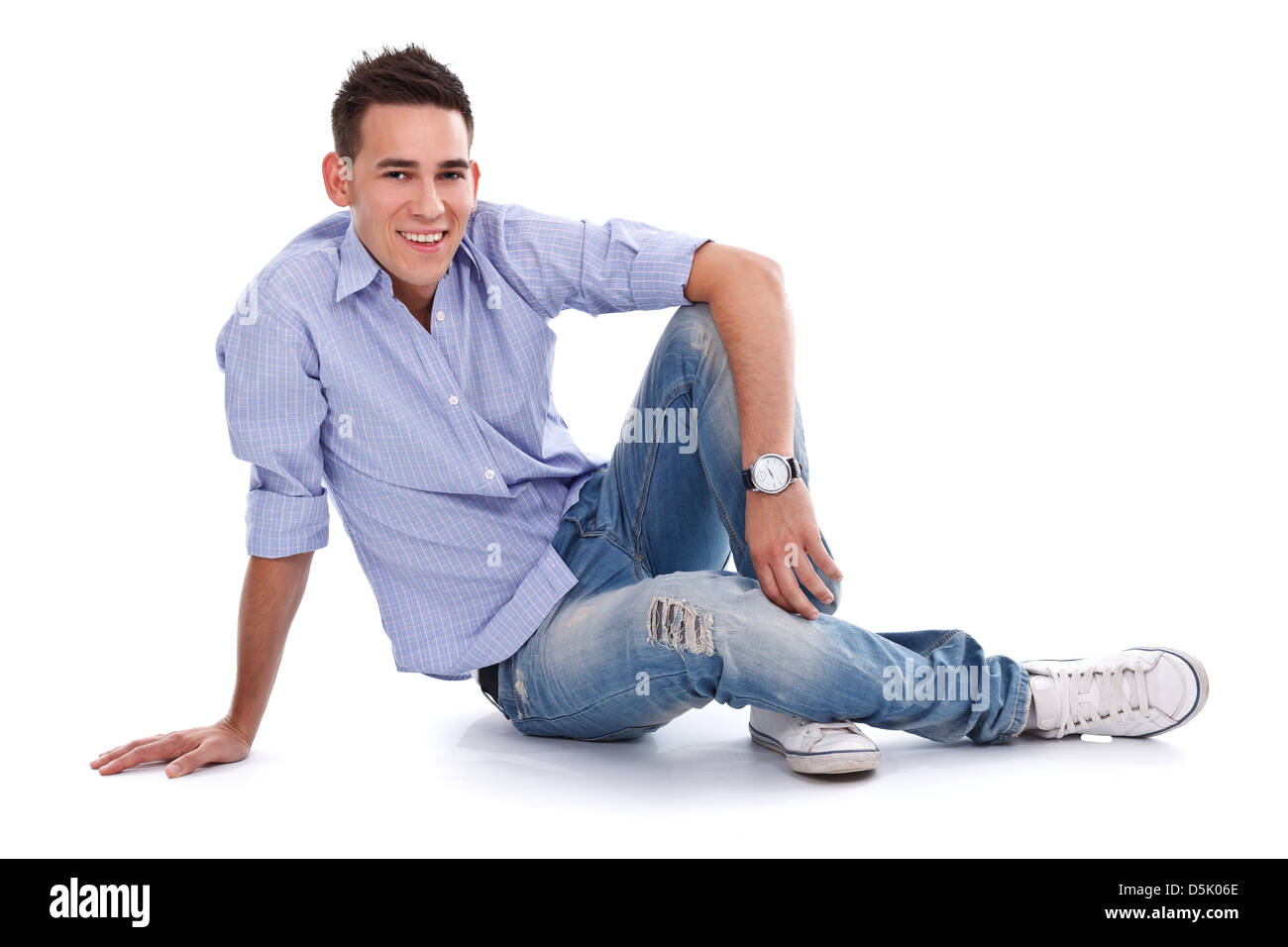 Smiling young man relaxing on the floor, looking to the camera on white background Stock Photo