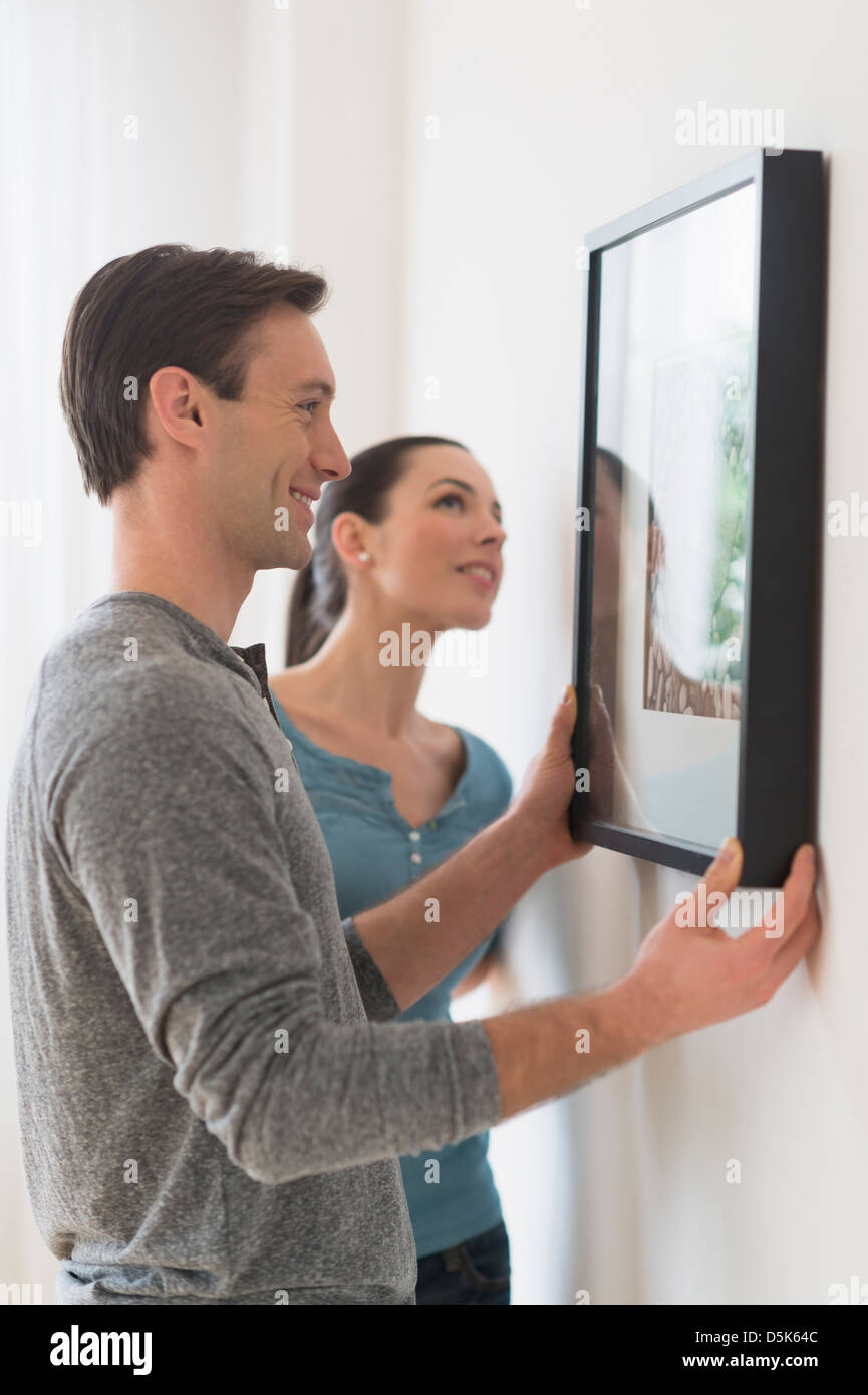 Couple hanging picture on wall Stock Photo