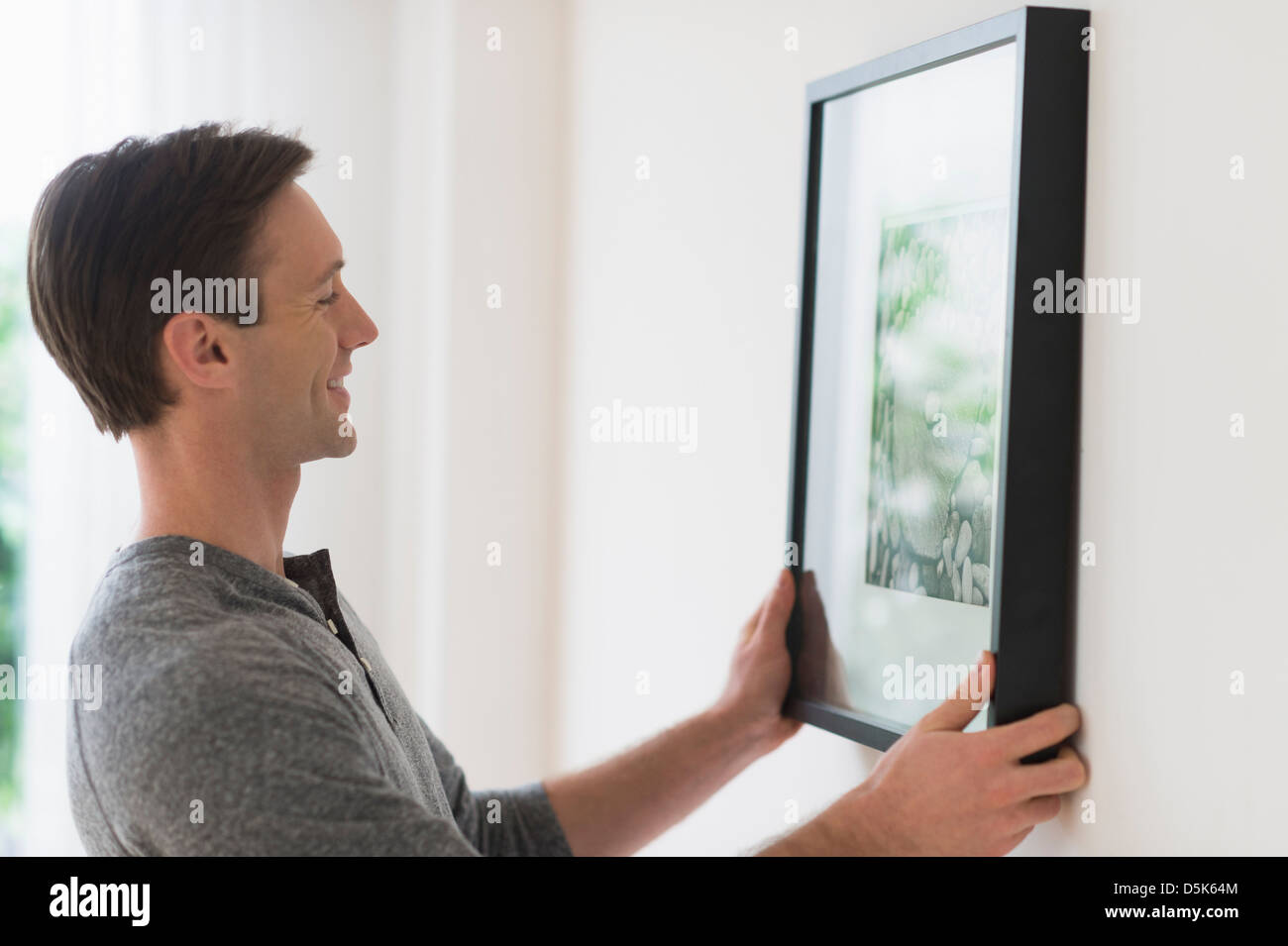 Man hanging picture on wall Stock Photo