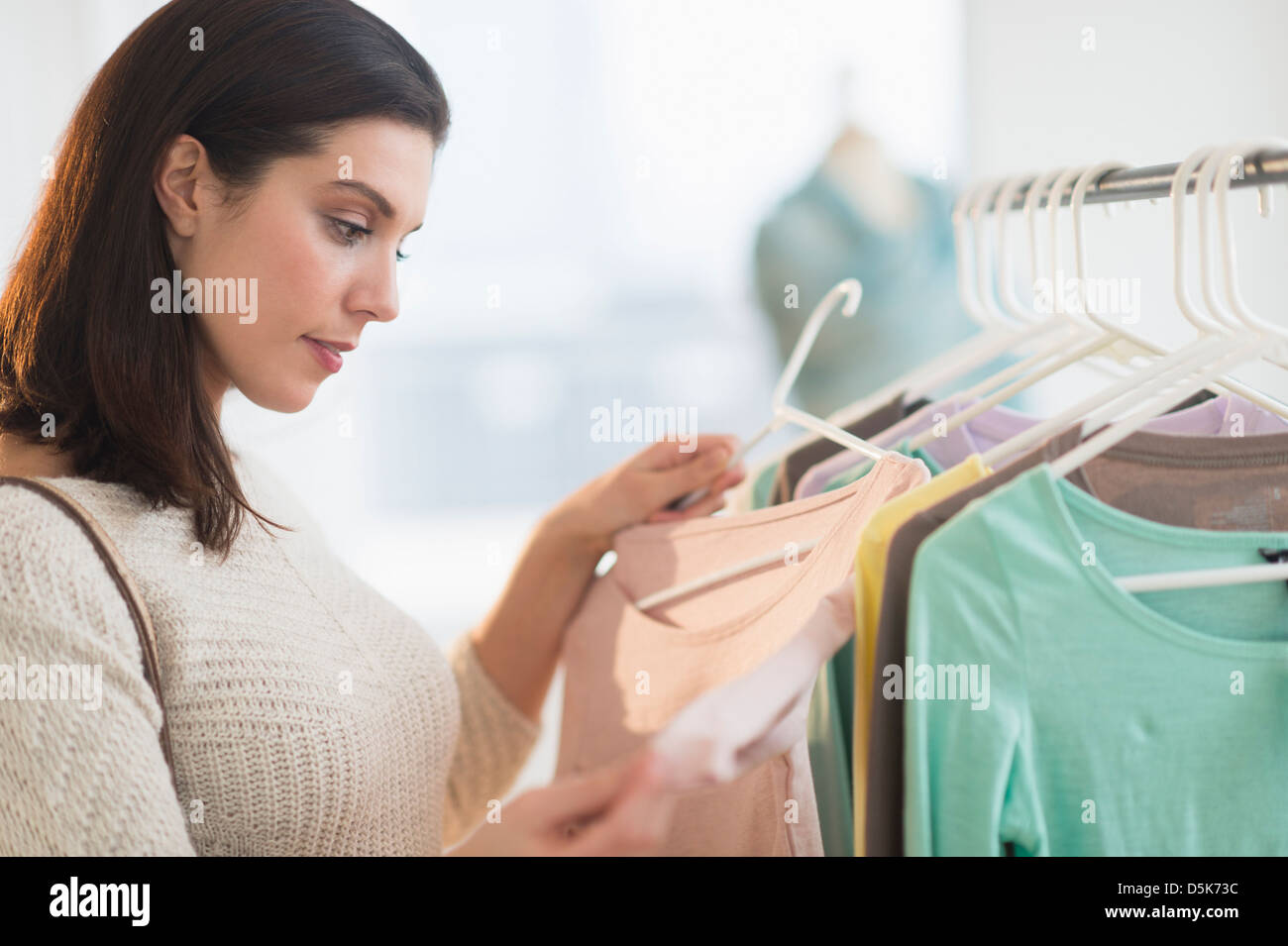 Woman looking at blouses at store Stock Photo