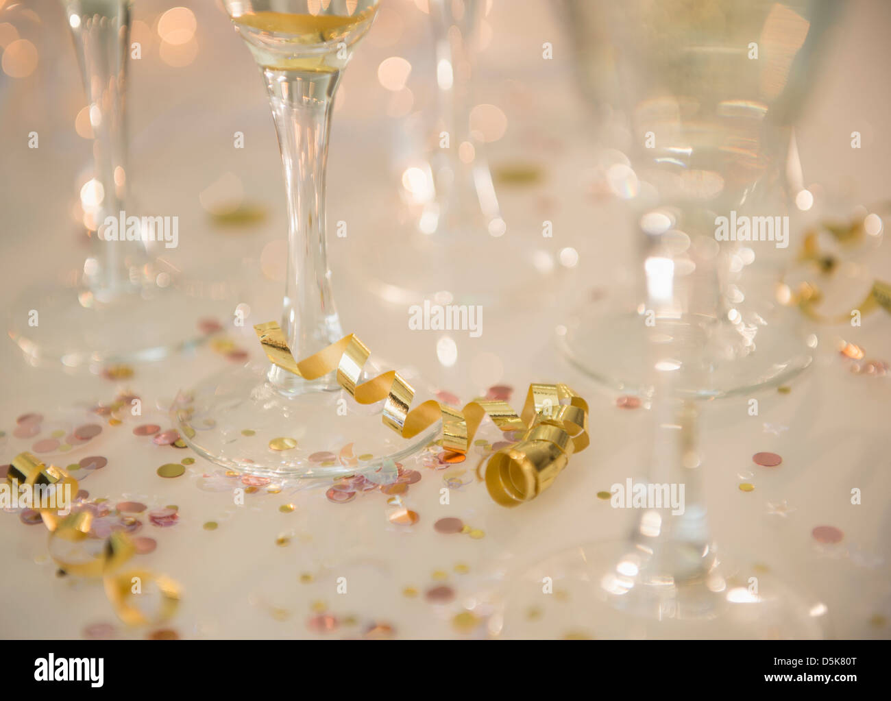 Champagne flutes on table decorated with confetti and streamer Stock