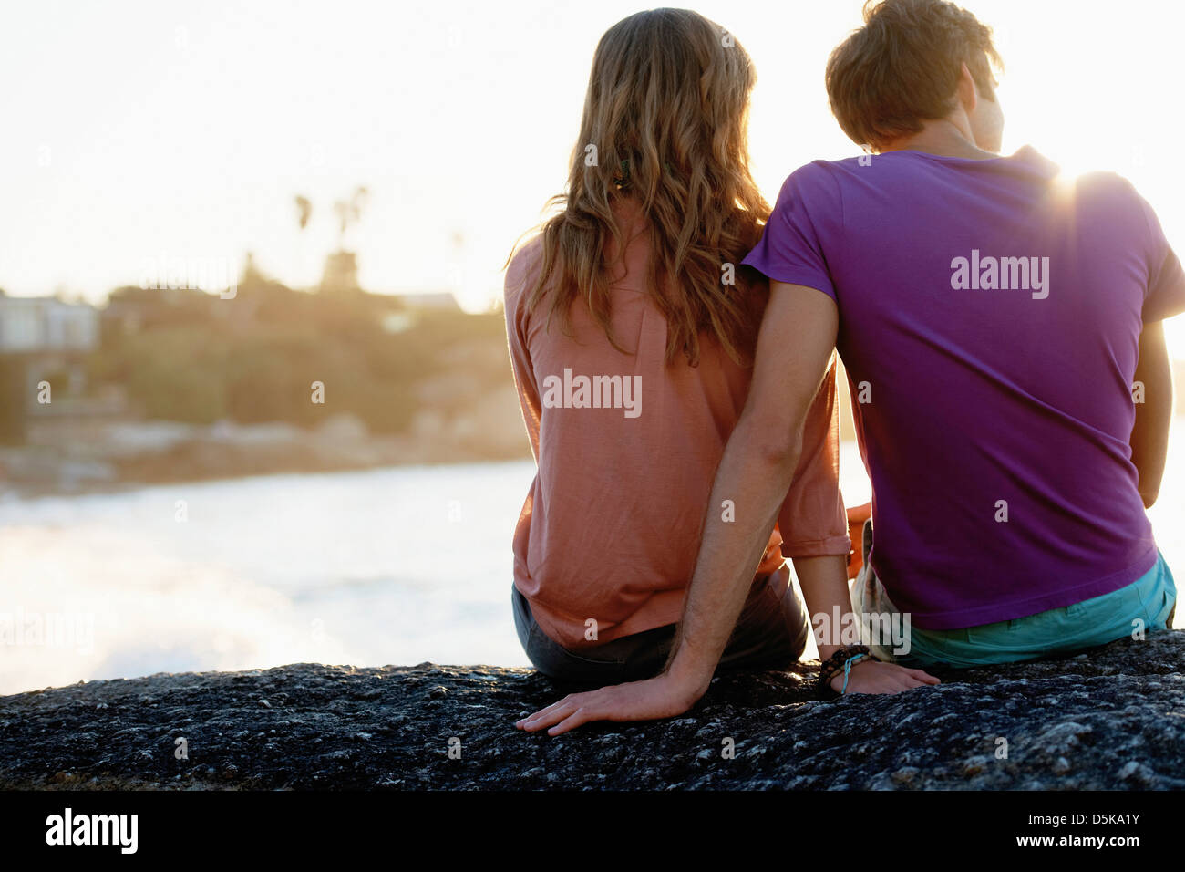 Rear view of young couple sitting at beach Stock Photo