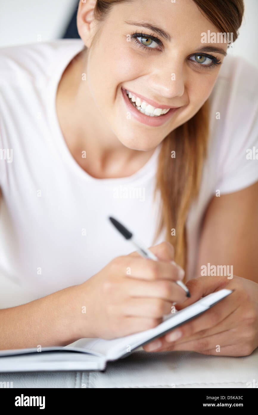 Portrait of young woman writing in notepad Stock Photo - Alamy