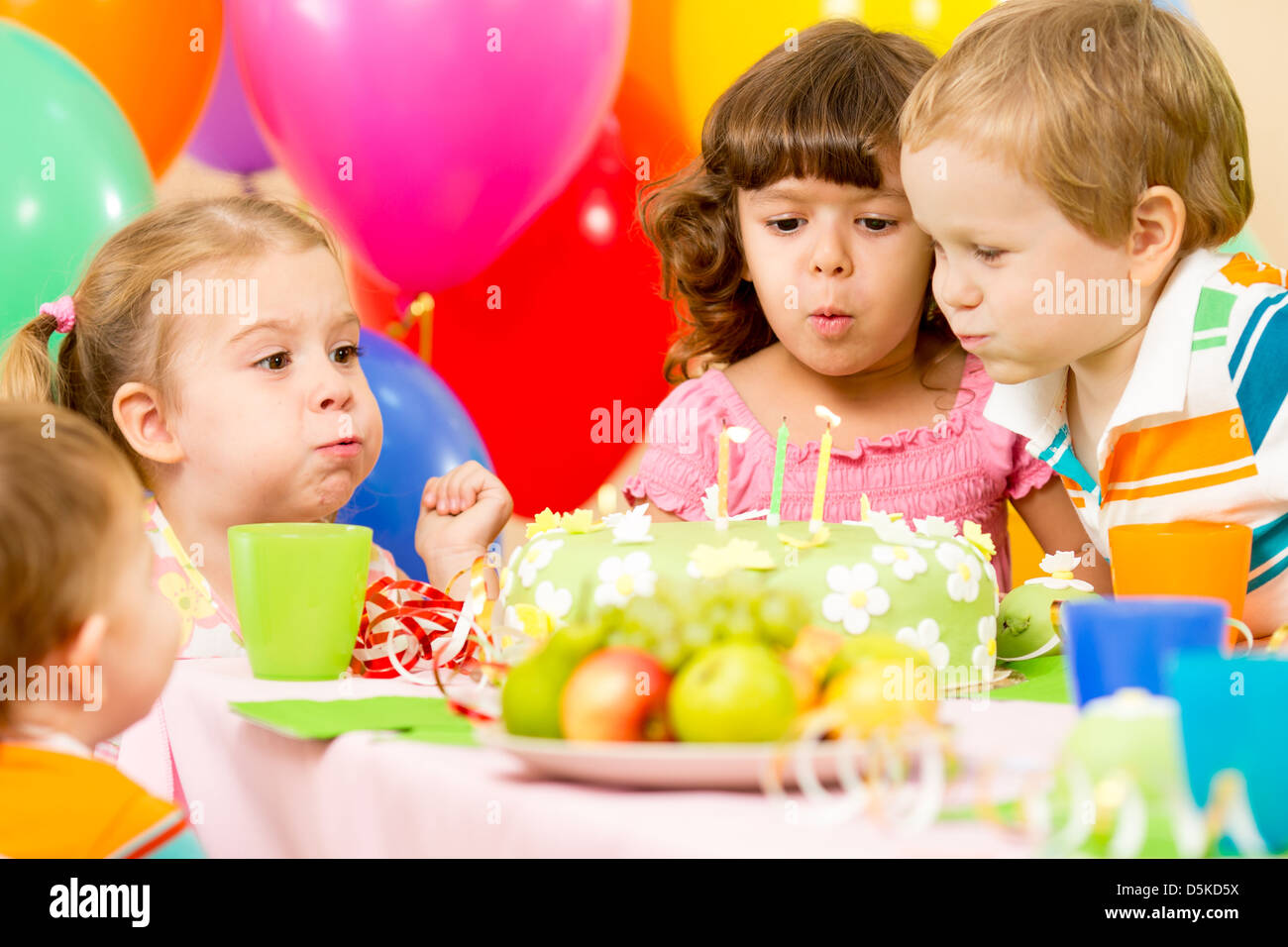 kids celebrating birthday party and blowing candles on cake Stock Photo