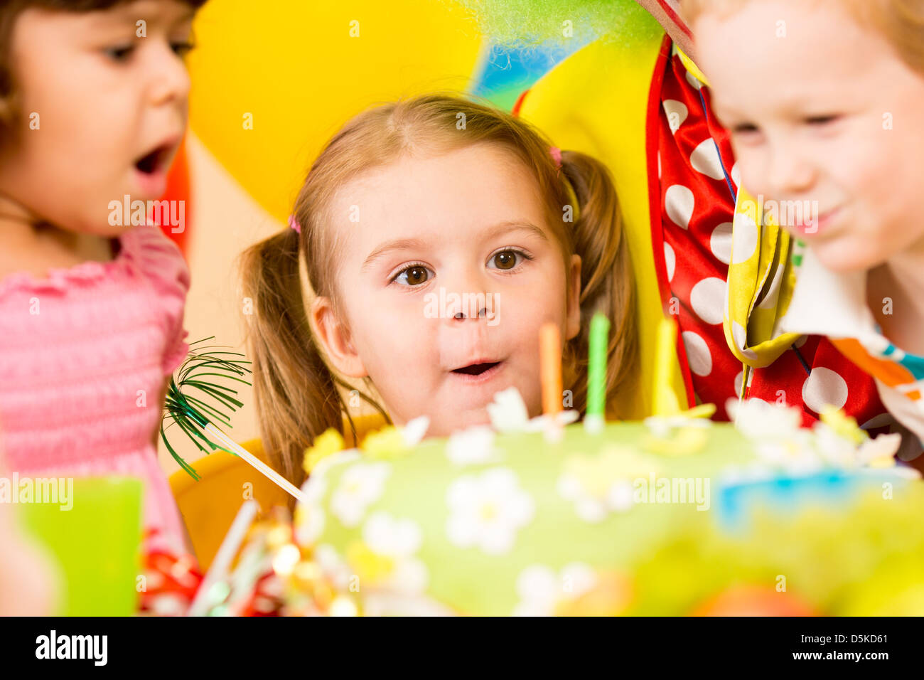 funny kids celebrating birthday party and blowing candles on cake Stock Photo