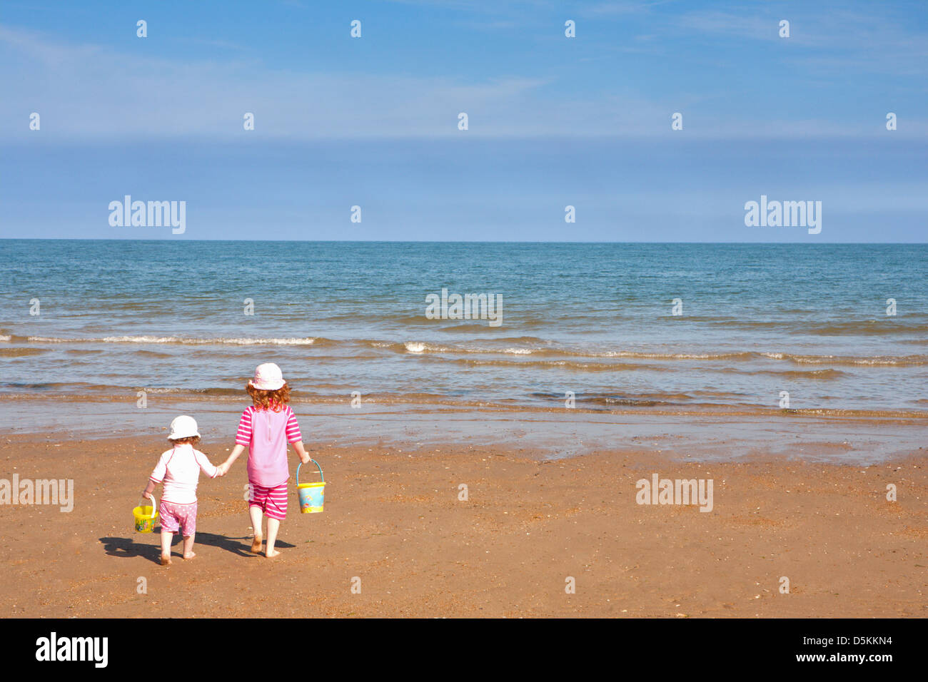 ENGLAND; NORFOLK; OLD HUNSTANTON; CHILDREN; TWO GIRLS; BEACH; HOLDING HANDS; SUMMER Stock Photo