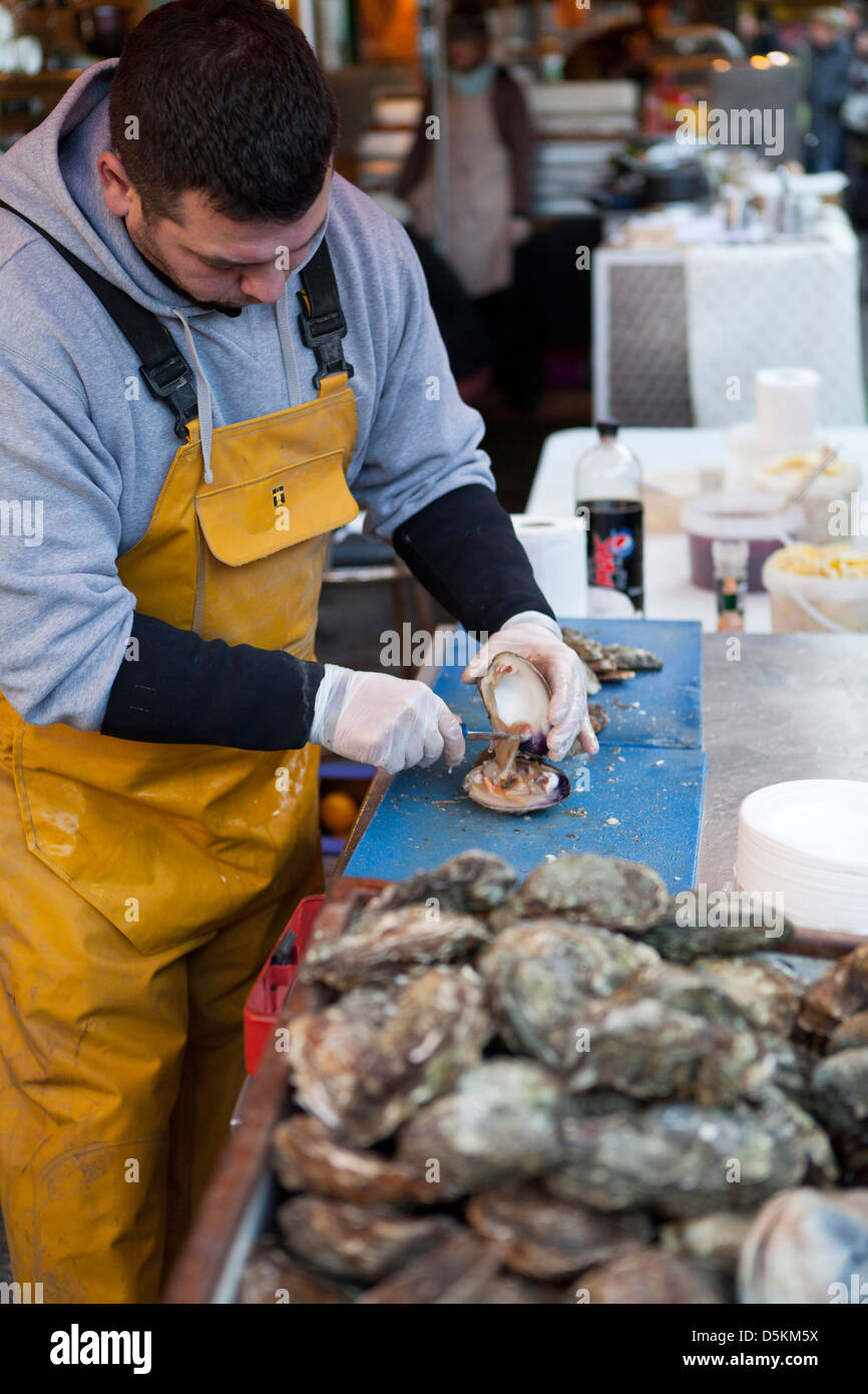 A fresh food stall on Borough Market. A man wearing apron and gloves