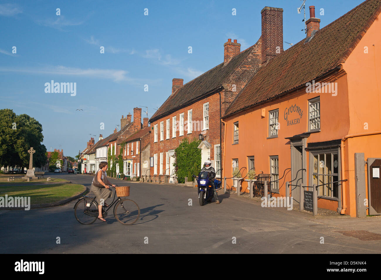 UK; NORFOLK; ENGLAND; BURNHAM MARKET; VILLAGE; SUMMER; NORTH NORFOLK; WOMAN; BICYCLE Stock Photo