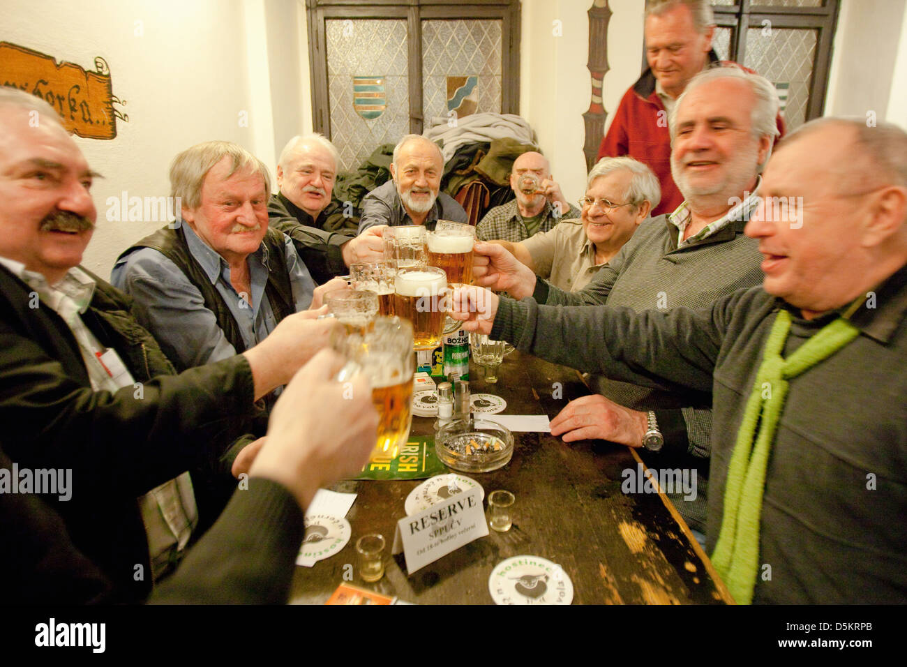 Prague - friends in a traditional Czech pub toasting with beer. Stock Photo