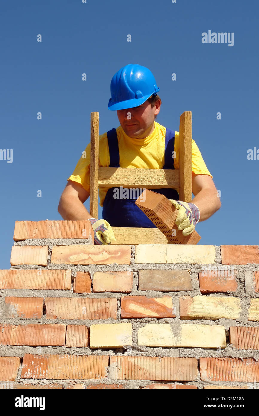 Mason laying bricks of house wall Stock Photo