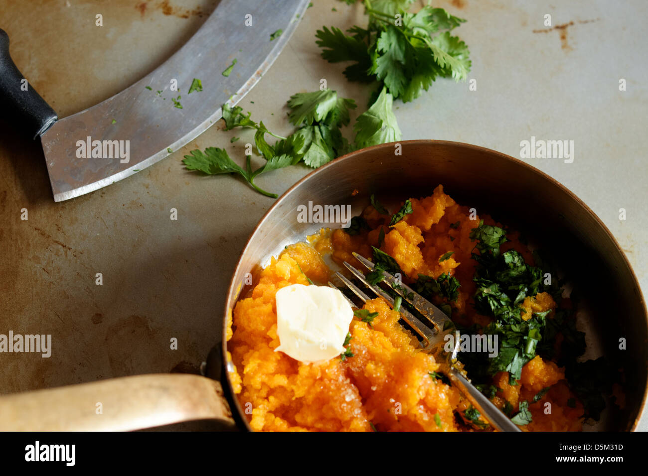 Mashed sweet potato or yam in a copper pan with coriander and a mezza