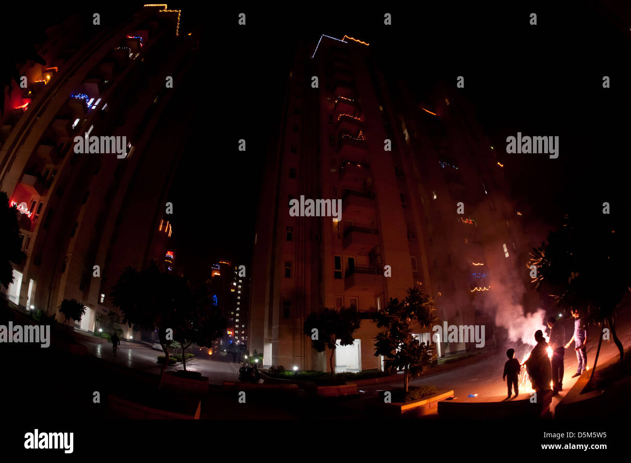 Divali lights decorate several blocks of apartments and a family set off fireworks, Gurgaon, India. Stock Photo