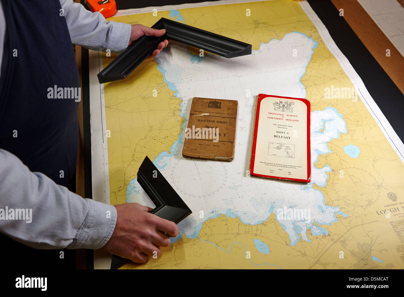 framer compares wooden frame samples with maps to frame in a framing workshop Stock Photo