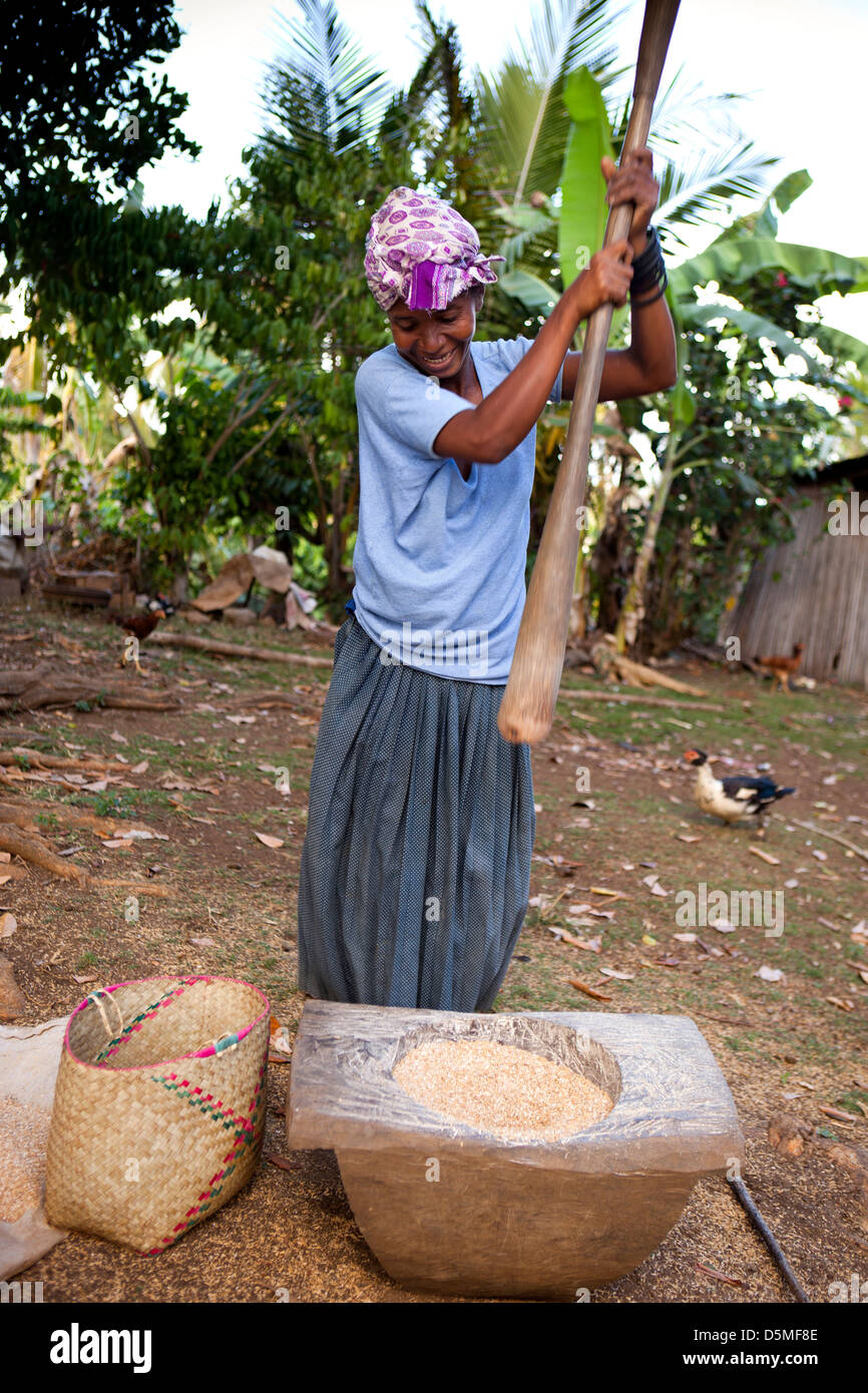 Madagascar, Nosy Be, Anjiamarango, fishing village woman pounding rice with large pestle Stock Photo
