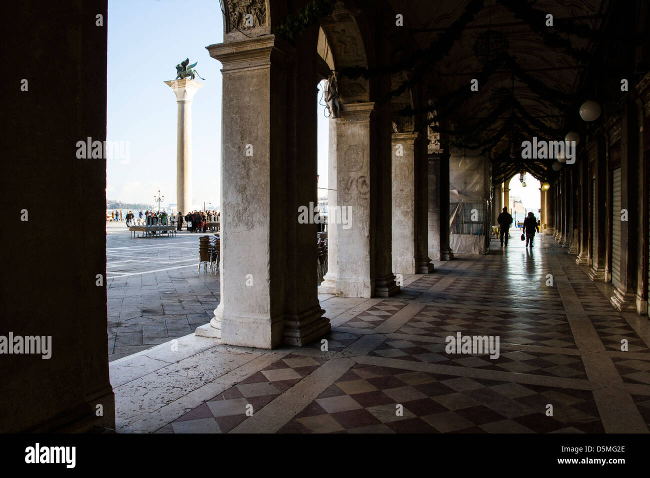 Column with the Lion of Saint Mark, symbol of the city, viewed from the arches of Procuratie Nuove. Stock Photo
