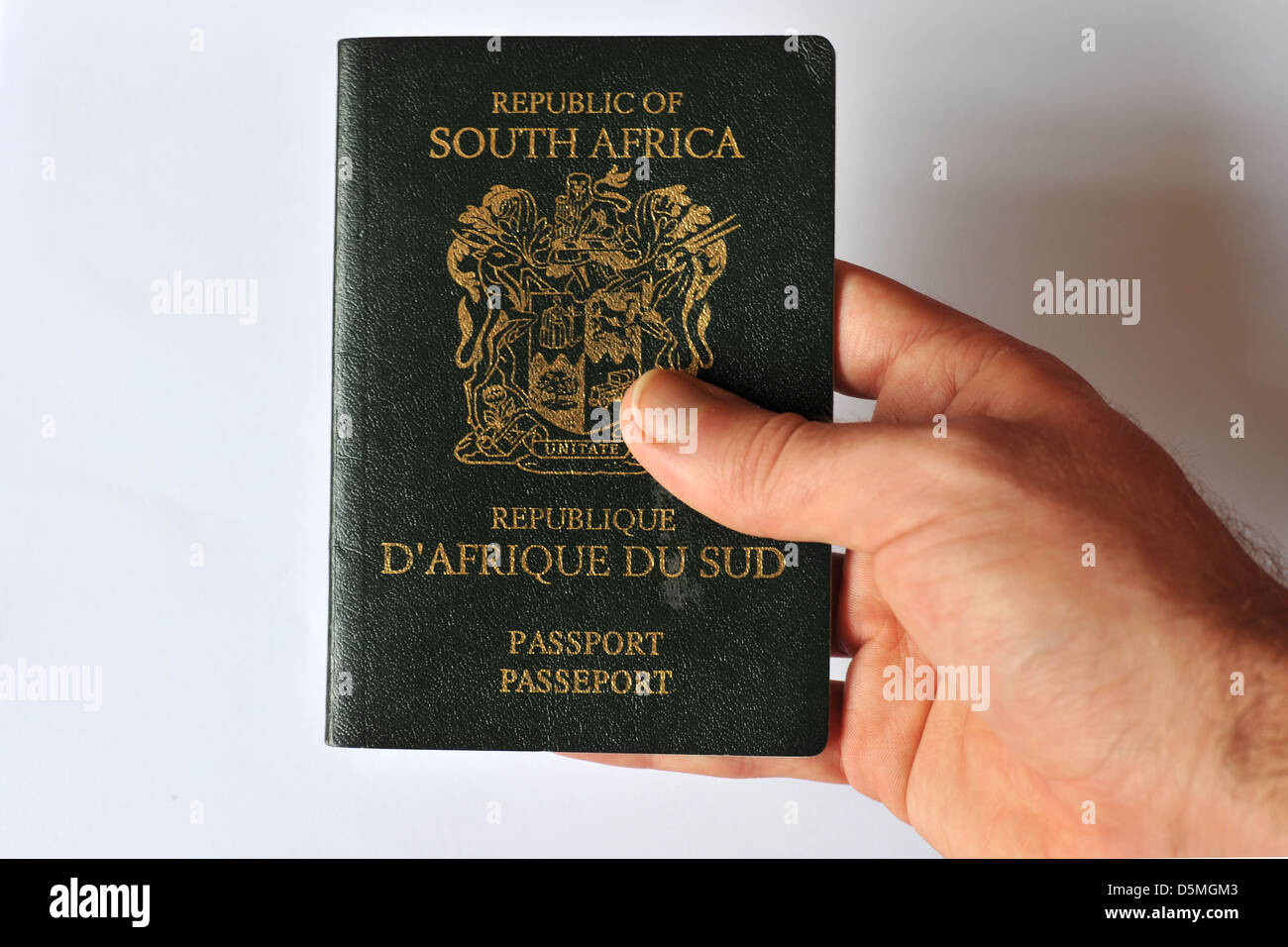 A white hand touching the old design of the South African Passport in the studio. Stock Photo