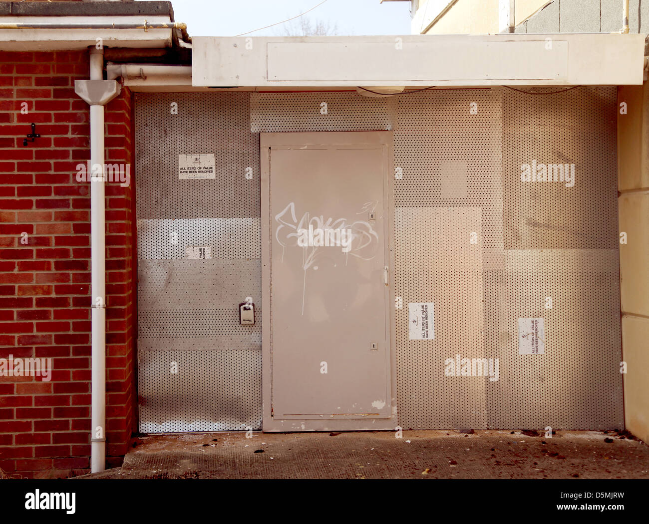 Securely shuttered up door to an empty building, with steel plates fixed over window and door openings Stock Photo