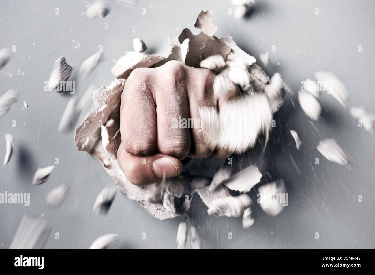 a wall is broken through by a fist Stock Photo