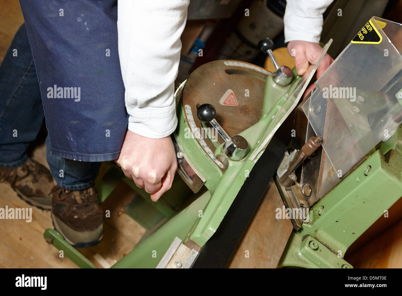 framer using morso picture framers guillotine to cut picture frame in a