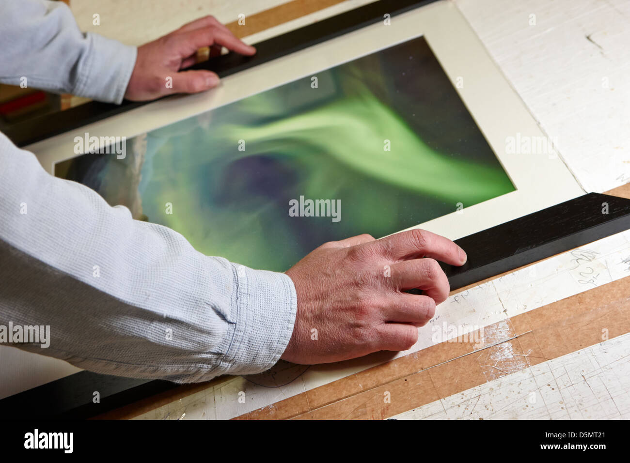framer preparing cut mouldings around a photograph in a framing workshop Stock Photo