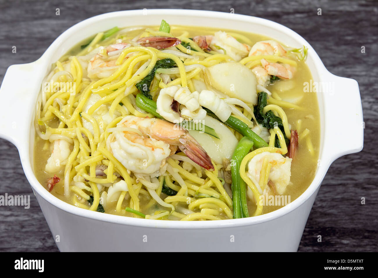 Hokkien Mee Stir Fry Yellow Noodles with Prawns Squids Fishcake and Green Vegetables Stock Photo