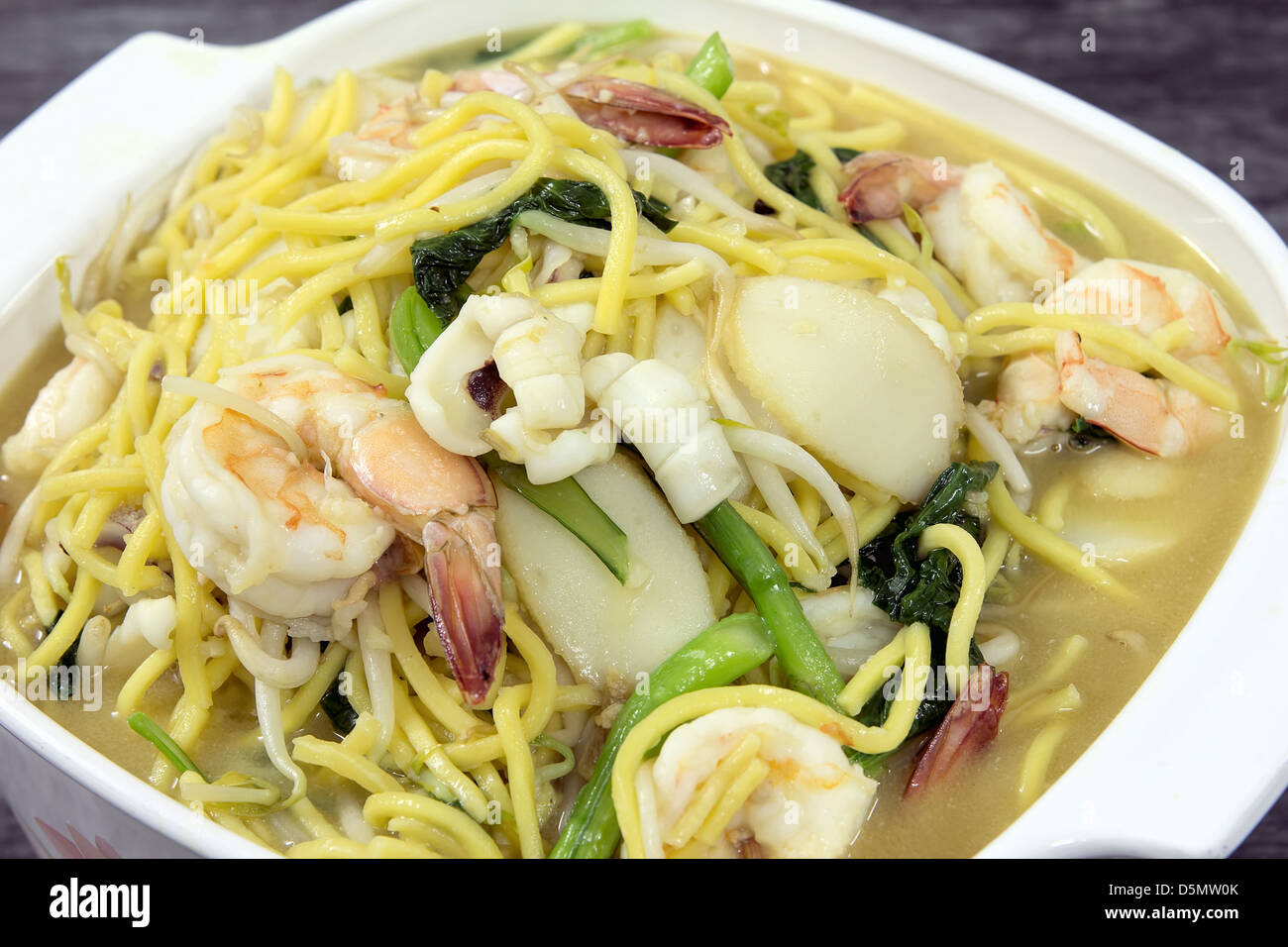 Hokkien Mee Stir Fry Yellow Noodles with Prawns Squids Fishcake and Green Vegetables Top View Closeup Stock Photo