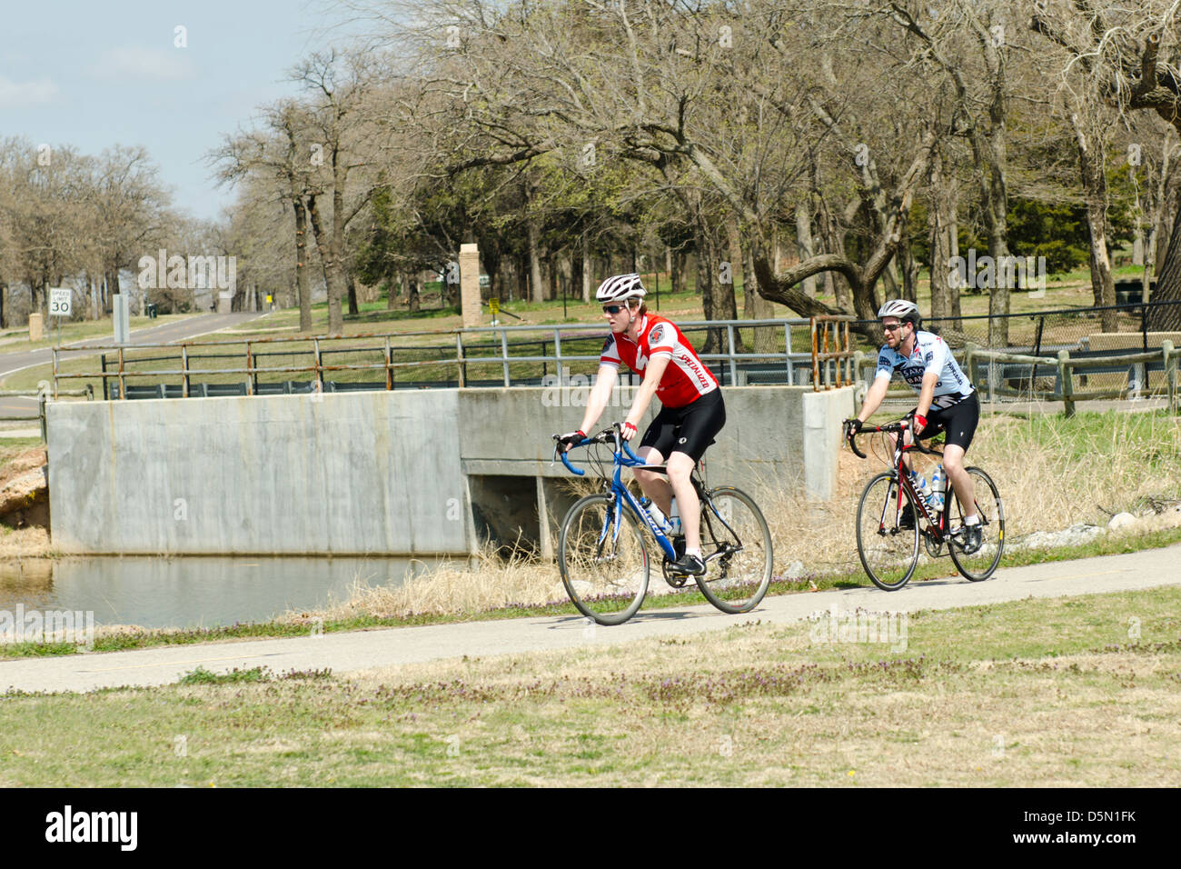 Two young Caucasian men bicycle on trails next to Overholser lake near Oklahoma City, Oklahoma, USA. Stock Photo
