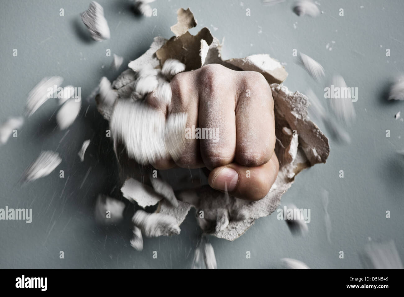 a wall is broken through by a fist Stock Photo