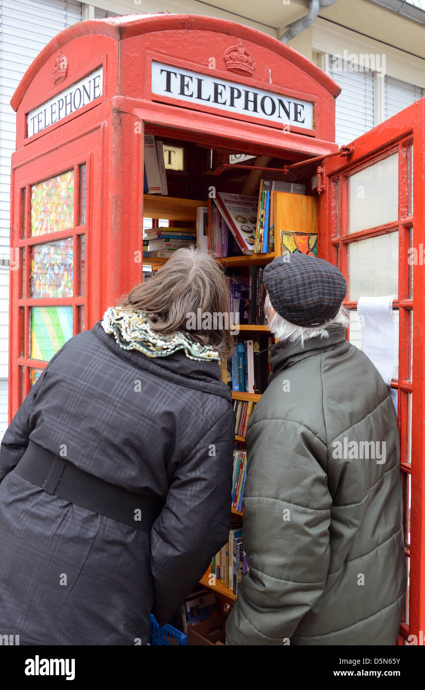 Pedestrians take a peek into an old English telephone booth which service as a public bookcase