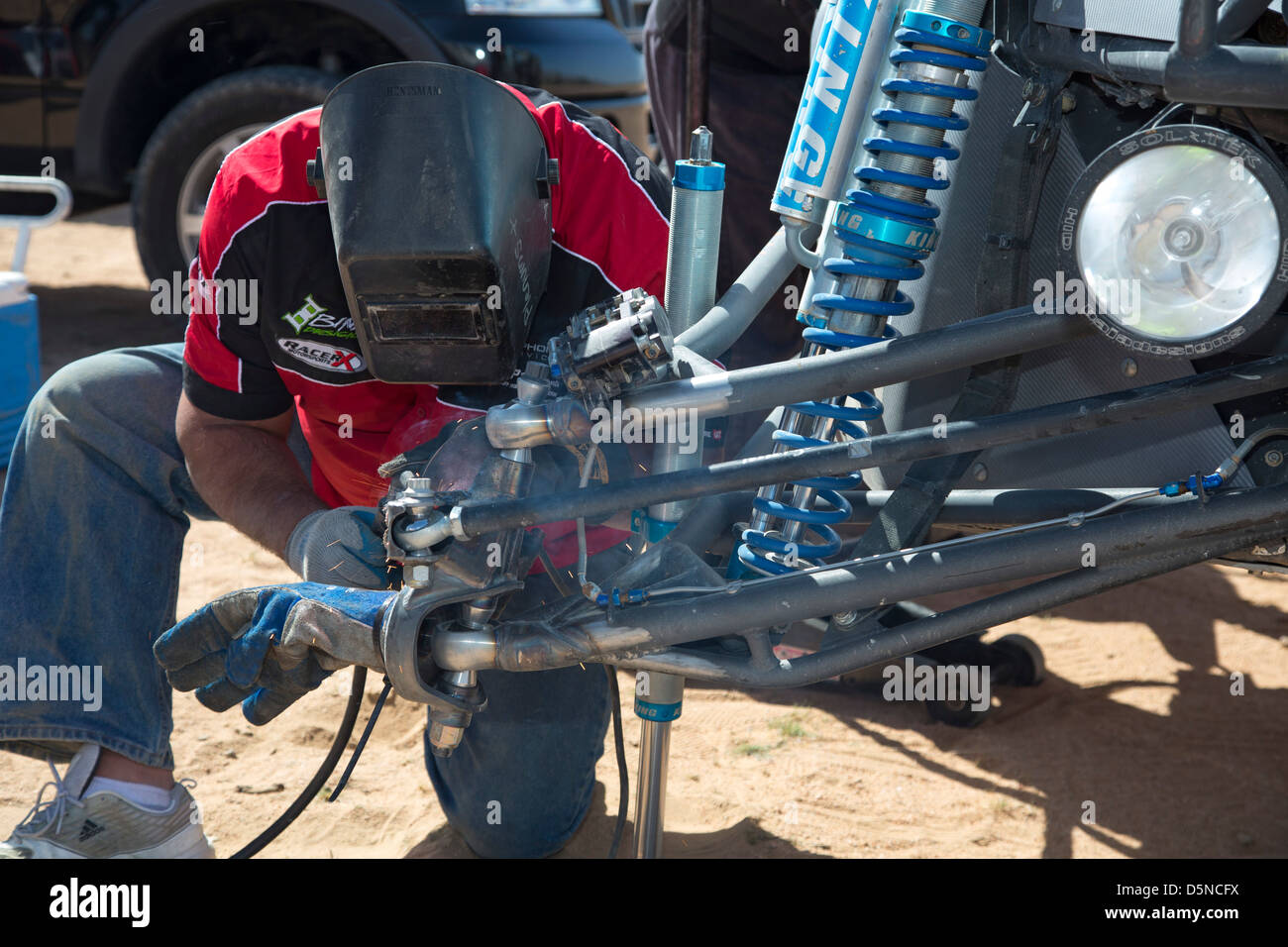 A welder works work on a car in the pits during the Mint 400 off-road auto race through the Mojave Desert Stock Photo
