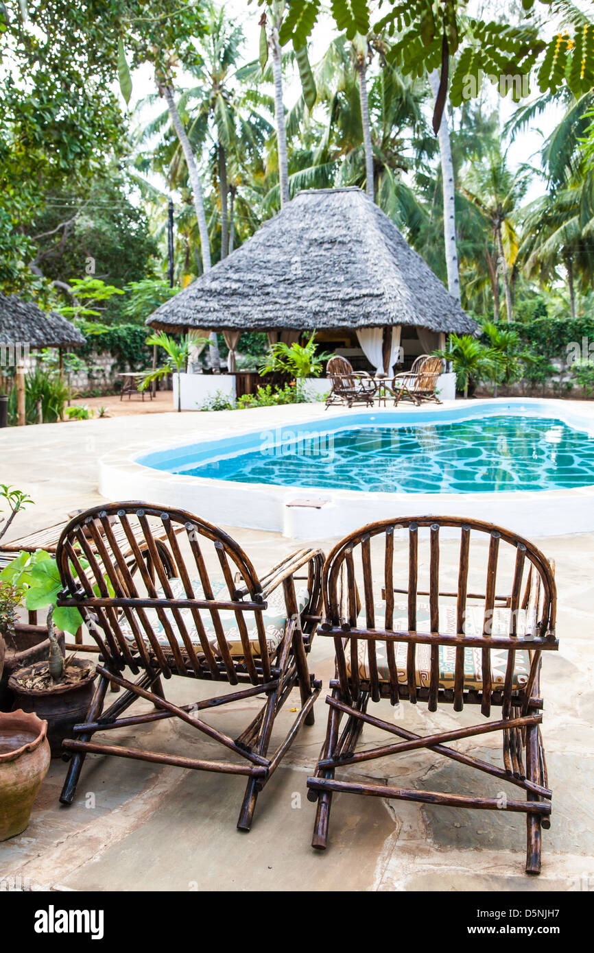 Elegant chairs made of wood close to a swimming pool inside a Kenyan