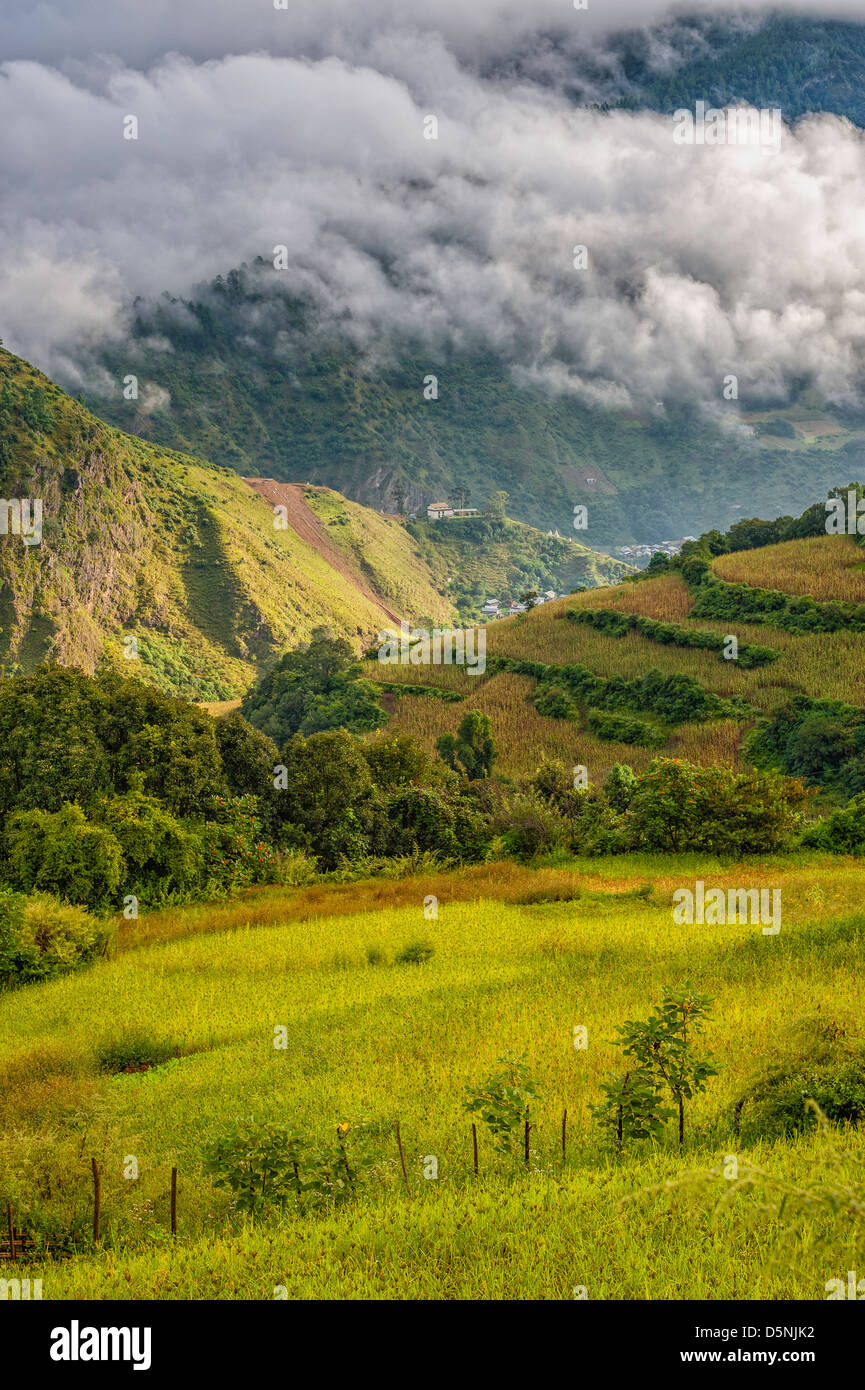 High mountains, deep valleys, maize cultivation, and a barely discernible village deep in the valley, near Dirang. Stock Photo