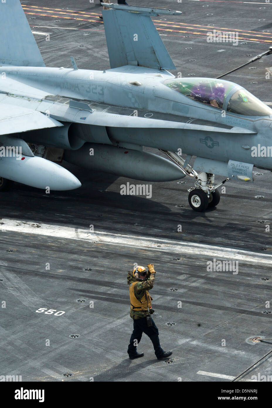A Sailor directs an F/A-18C Hornet fighter on the flight deck of the aircraft carrier USS Nimitz April 4, 2013 in the Pacific Ocean. Stock Photo