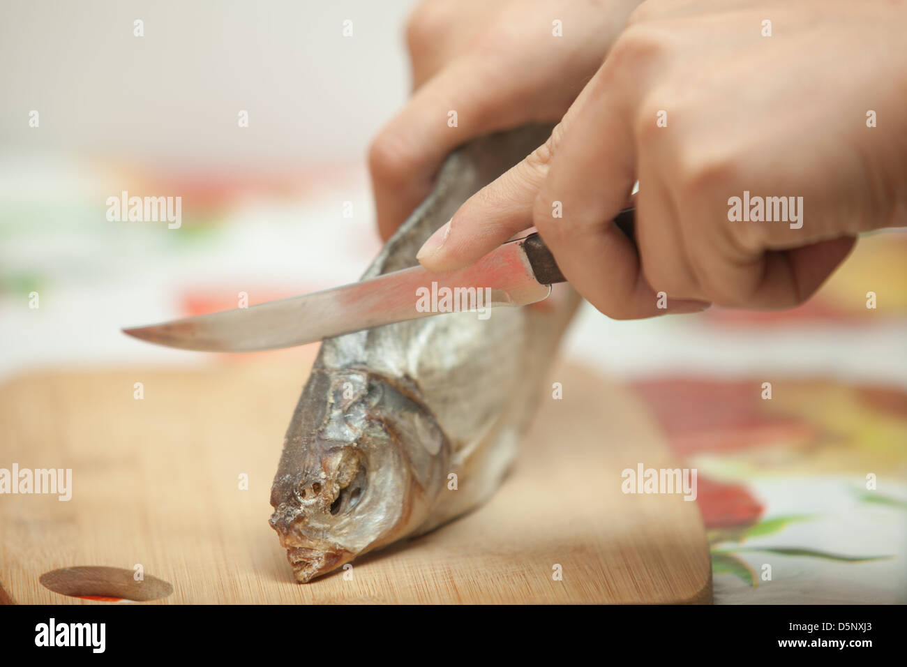 Man's hands with a knife cut the fish on the kitchen blackboard Stock Photo