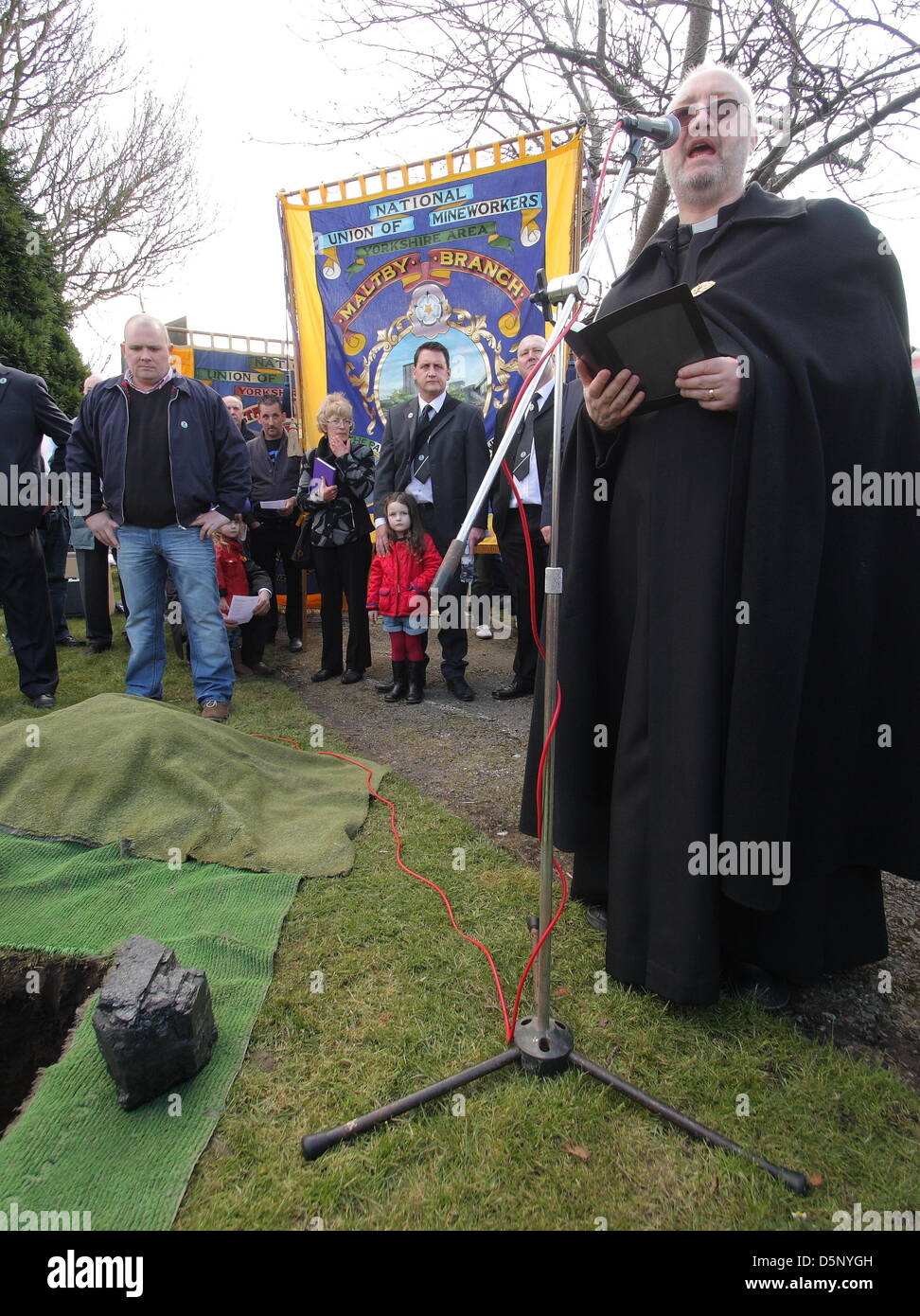 Maltby, UK. 6th April 2013. Reverand Peter Craig-Wild leads a service at Maltby Cemetery to mark the closure of Maltby Colliery.  A piece of coal, dug recently from the pit, was buried alongside the Grave of the Unknown Miner on which two wreaths were laid. Credit: Matthew Taylor / Alamy Live News Stock Photo