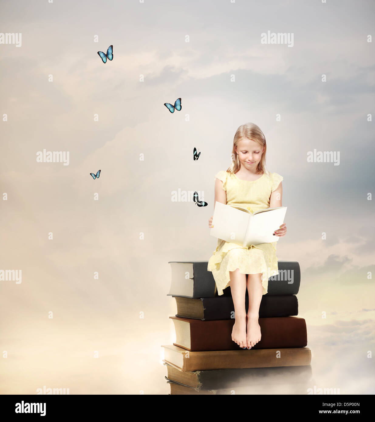 Little Blonde Girl Reading a Book on Top of Books Stock Photo