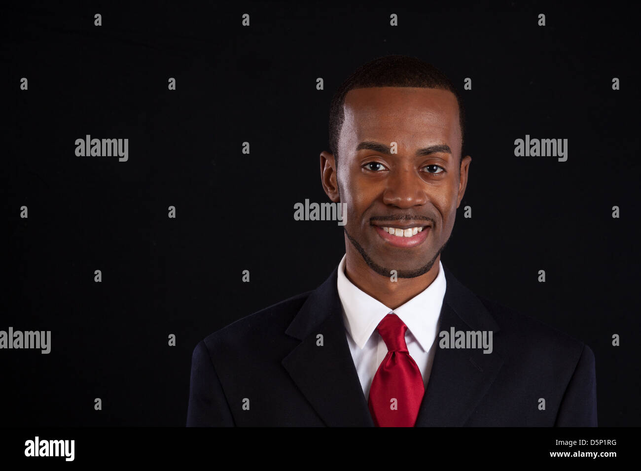 Black man in dark suit, white shirt and red tie, a successful, prosperous businessman, looking thoughtful and happy Stock Photo