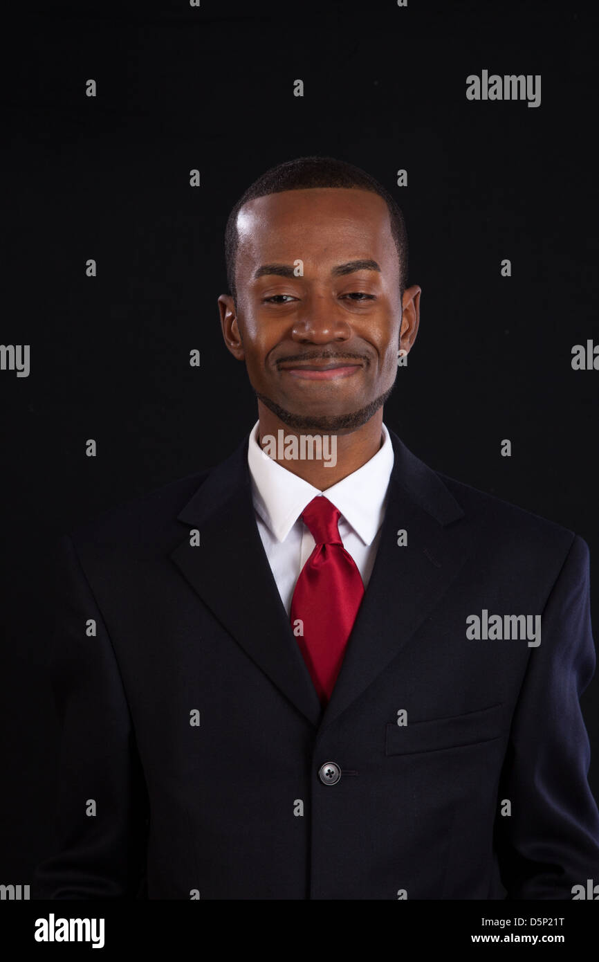 Black man in dark suit, white shirt and red tie, a successful, prosperous businessman, looking happy with himself Stock Photo