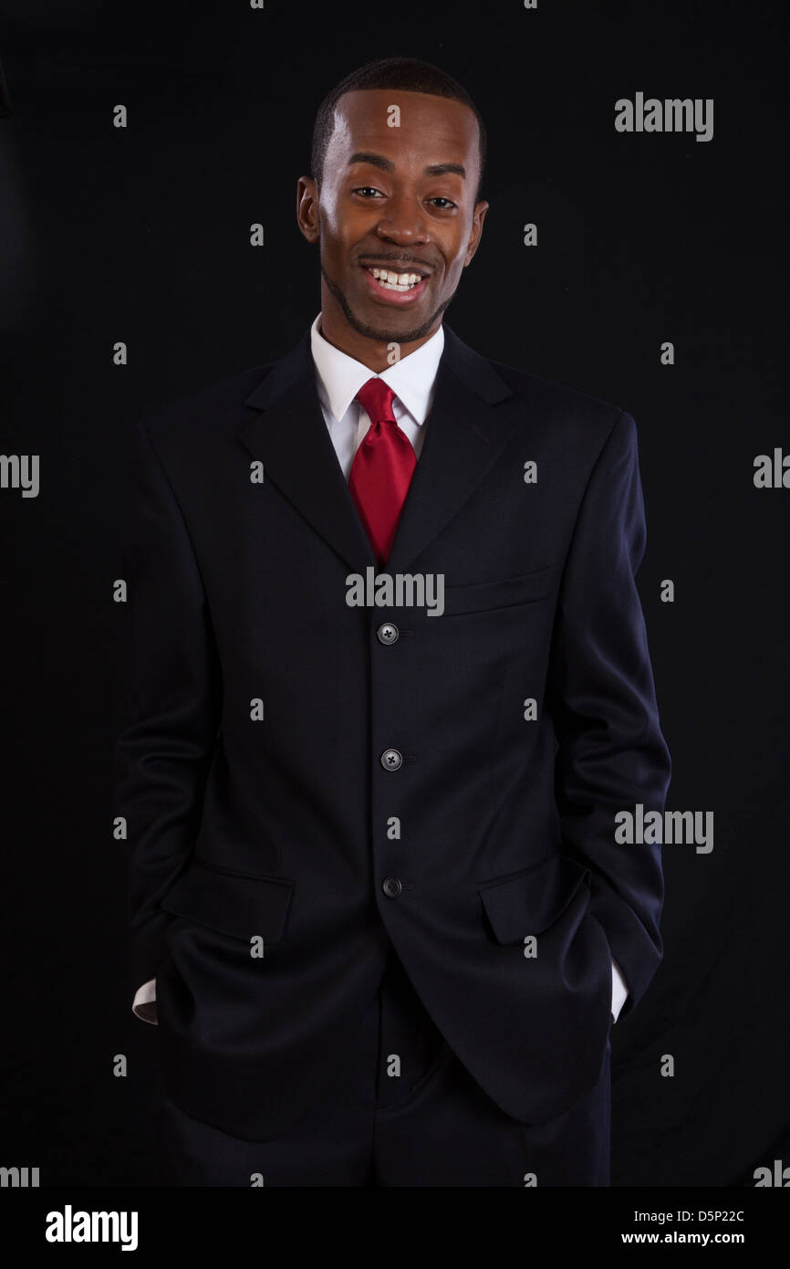 Black man in dark suit, white shirt and red tie, a successful, prosperous businessman, looking happy Stock Photo