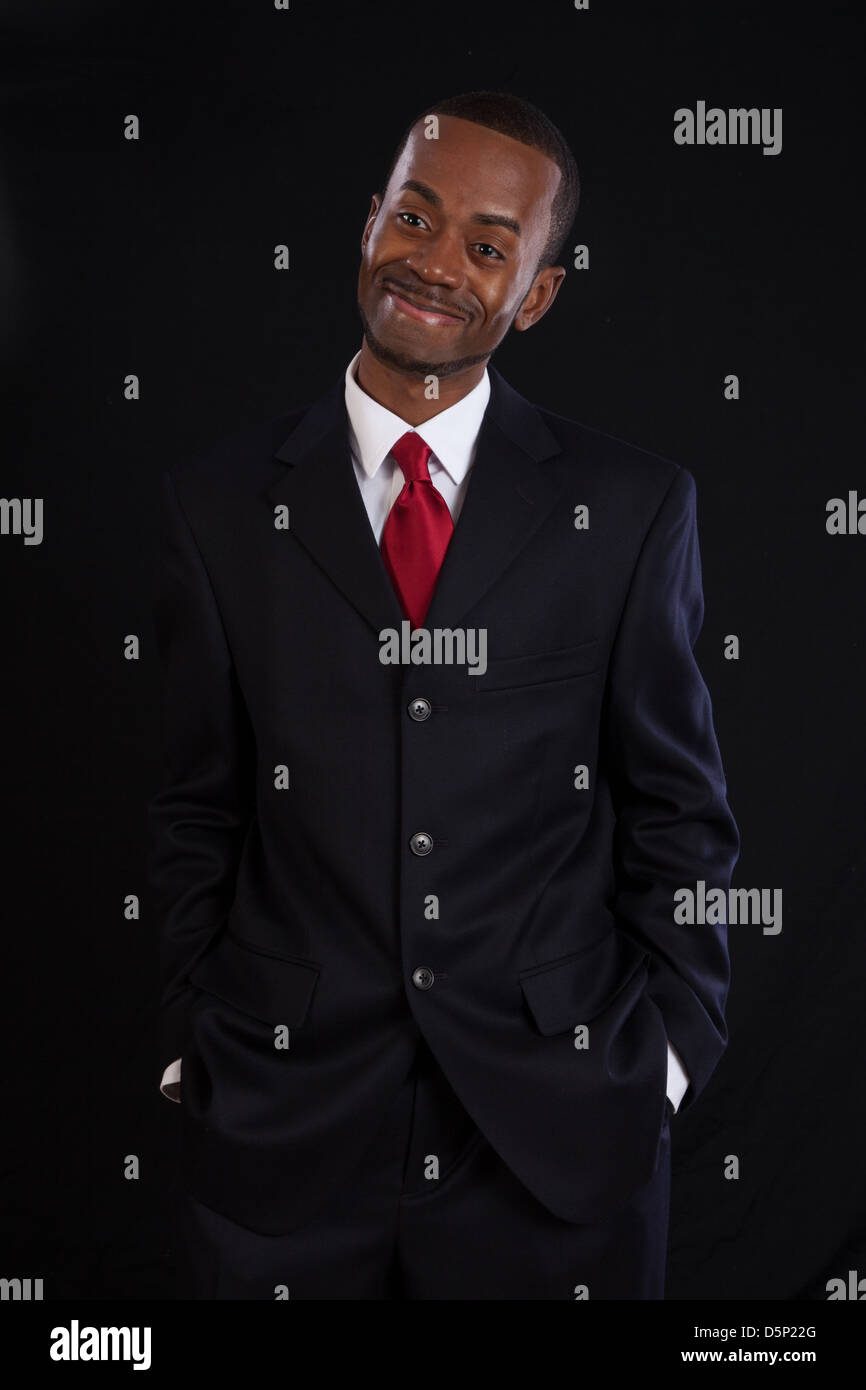 Black man in dark suit, white shirt and red tie, a successful, prosperous businessman, looking happy Stock Photo