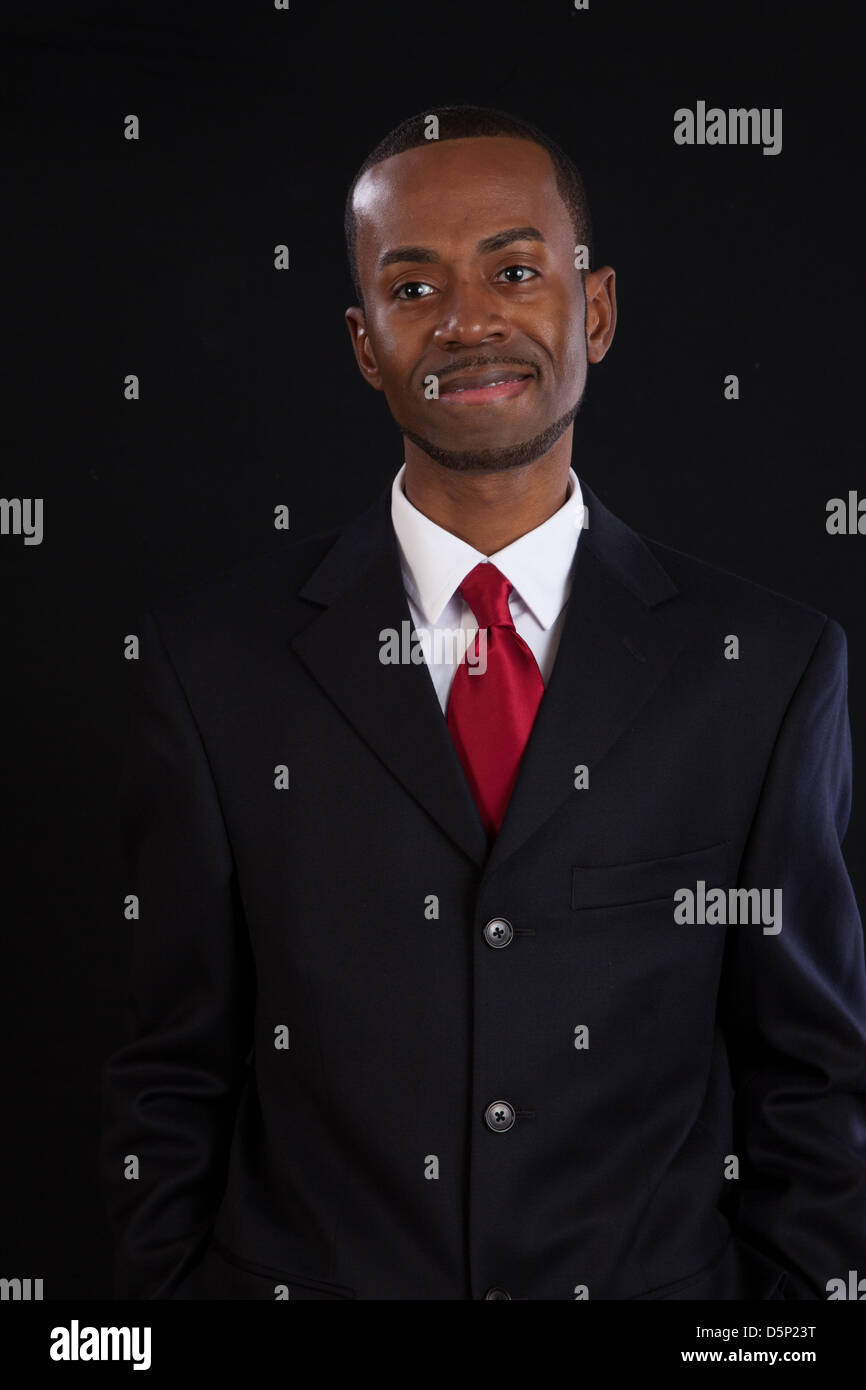 Black man in dark suit, white shirt and red tie, a successful, prosperous businessman, looking pleased Stock Photo