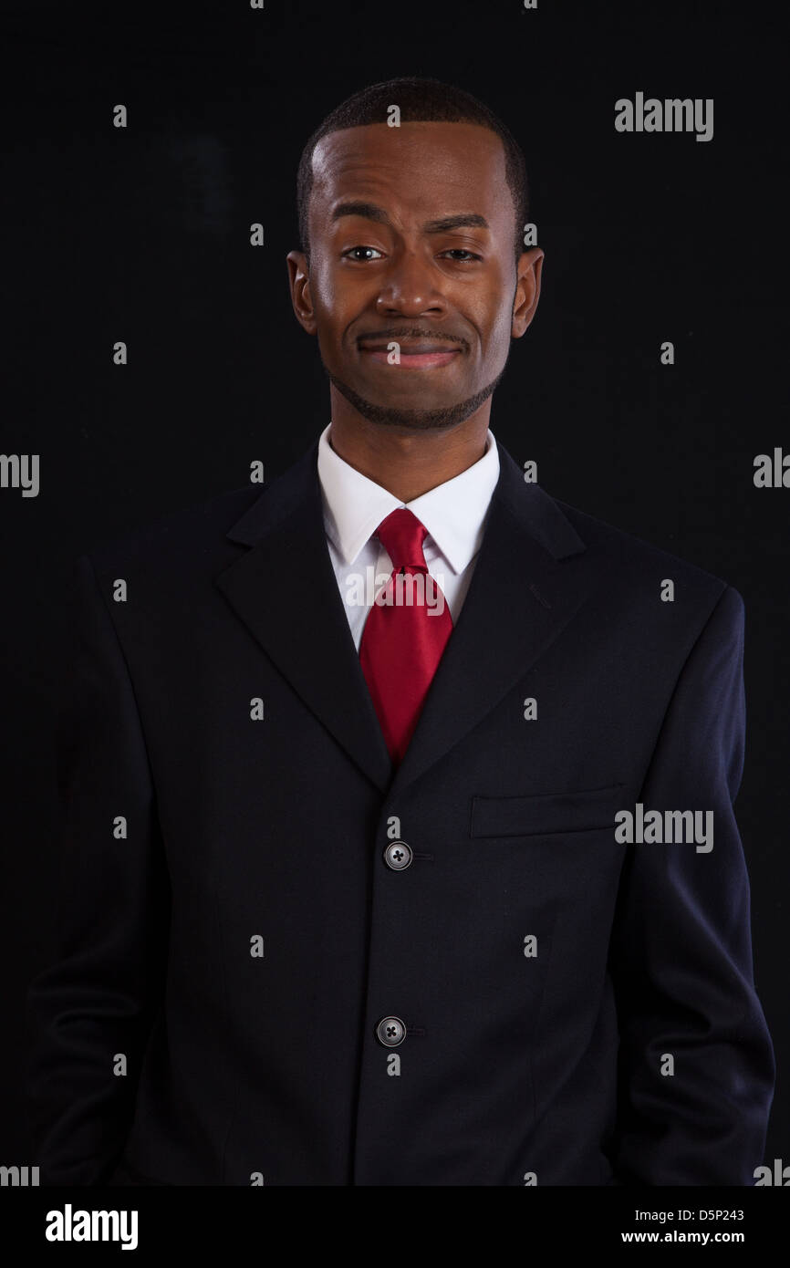 Black man in dark suit, white shirt and red tie, a successful, prosperous businessman, looking pleased Stock Photo
