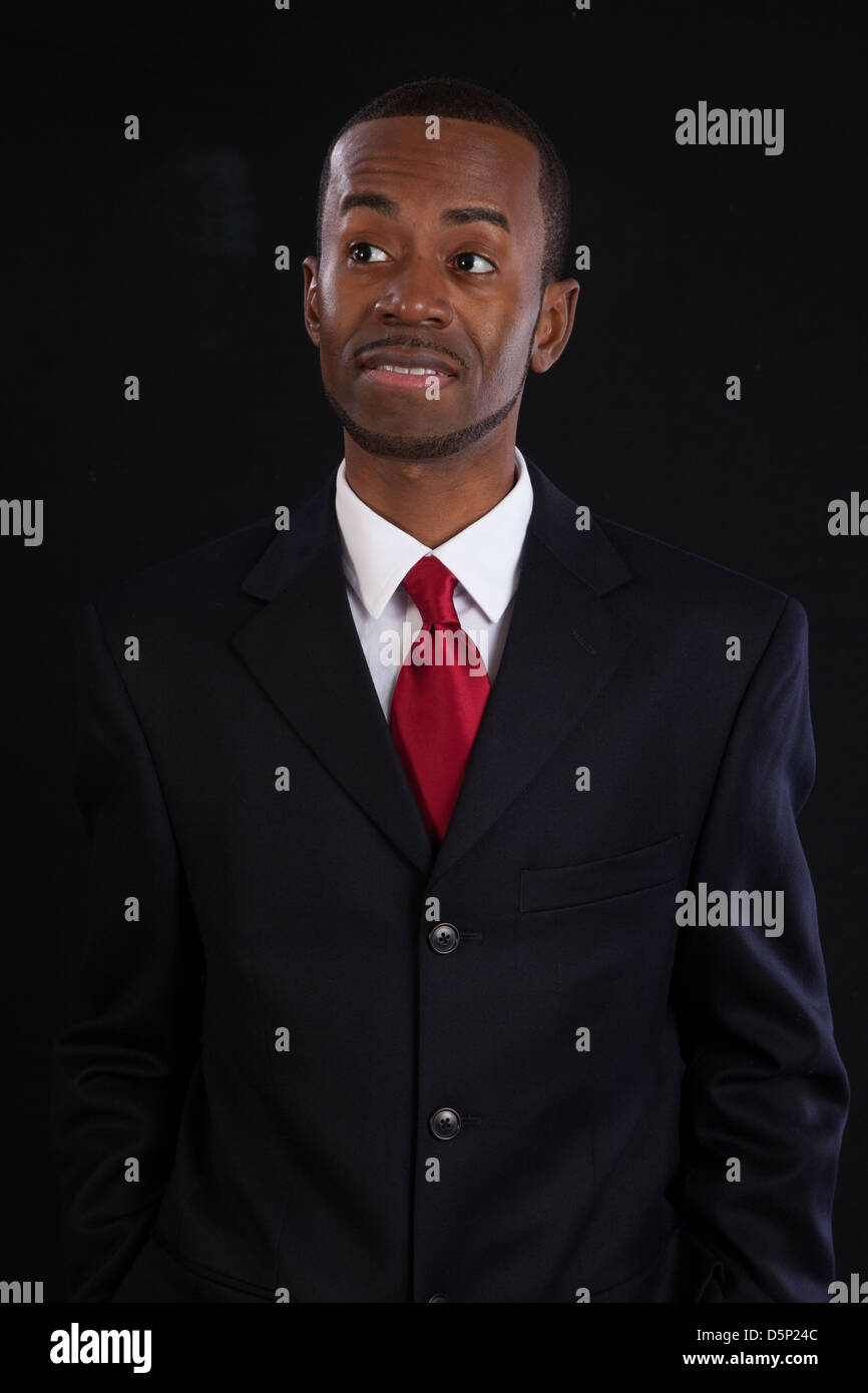 Black man in dark suit, white shirt and red tie, a successful, prosperous businessman, wondering and thoughtful Stock Photo