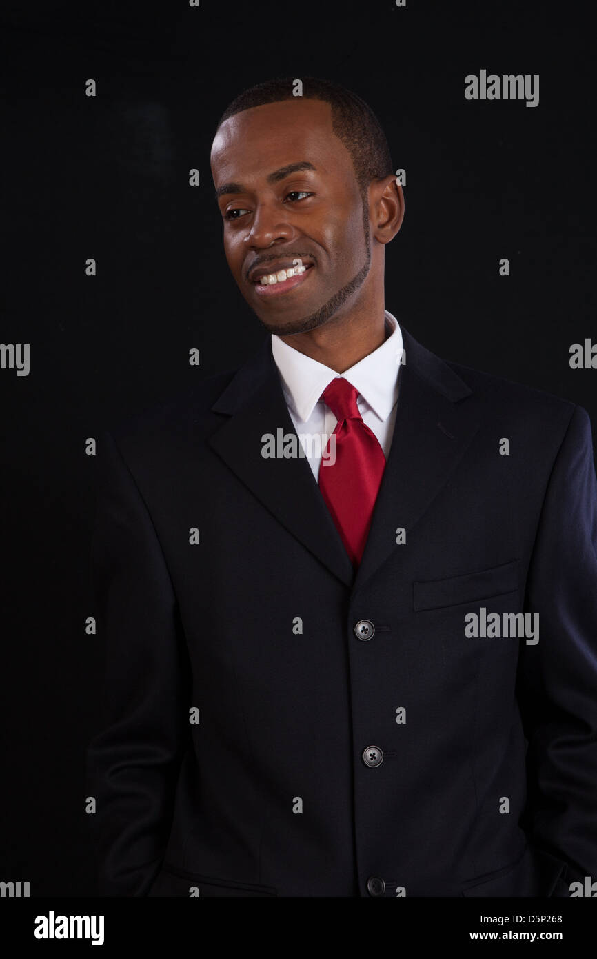 Black man in dark suit, white shirt and red tie, a successful, prosperous businessman, looking pleased with himself Stock Photo