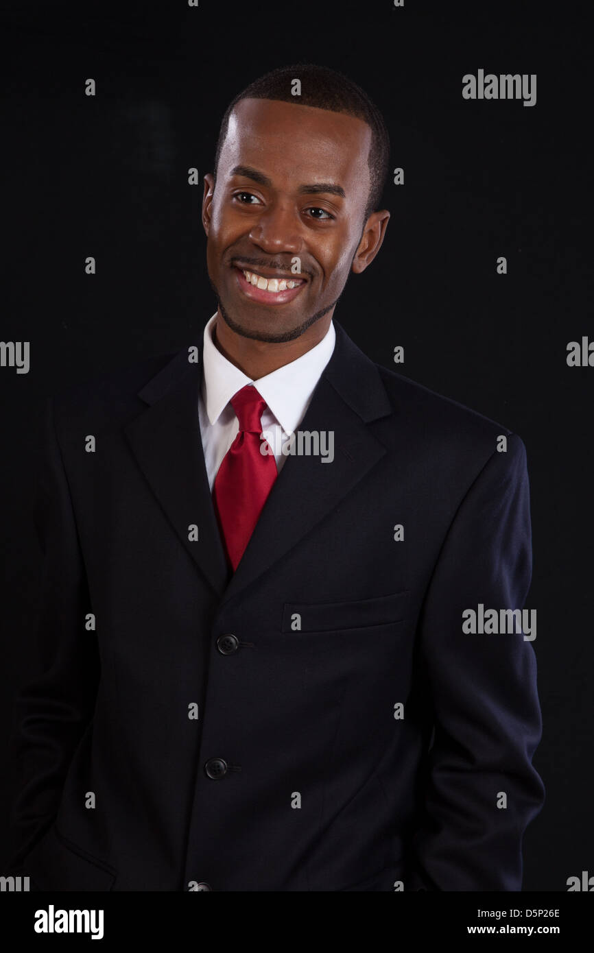 Black man in dark suit, white shirt and red tie, a successful, prosperous businessman, looking pleased with himself Stock Photo