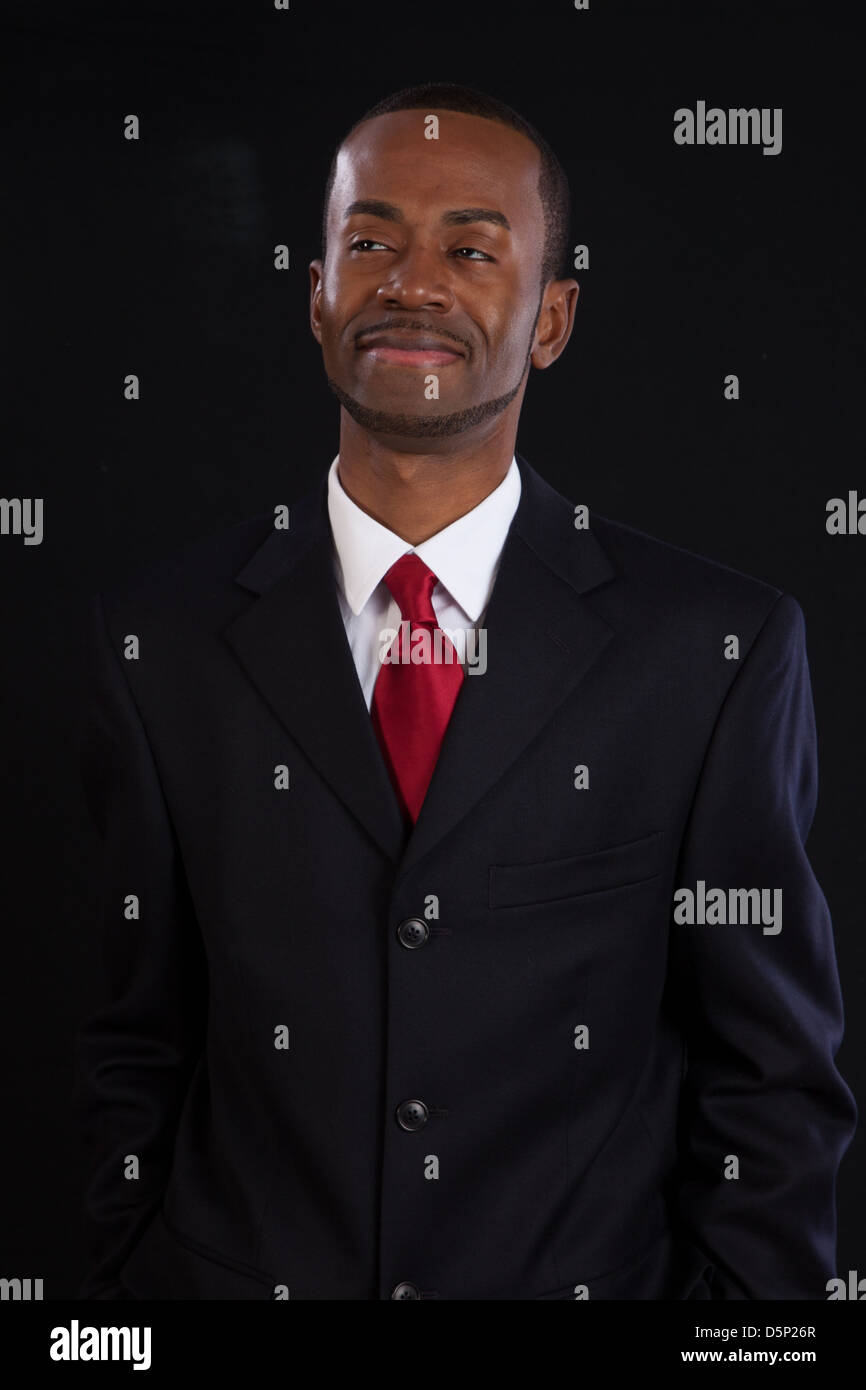 Black man in dark suit, white shirt and red tie, a successful, prosperous businessman, looking thoughtful Stock Photo