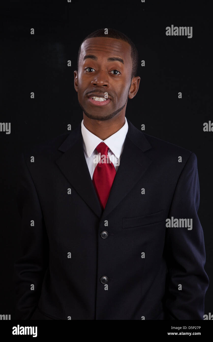Black man in dark suit, white shirt and red tie, a successful, prosperous businessman, talking to the camera Stock Photo