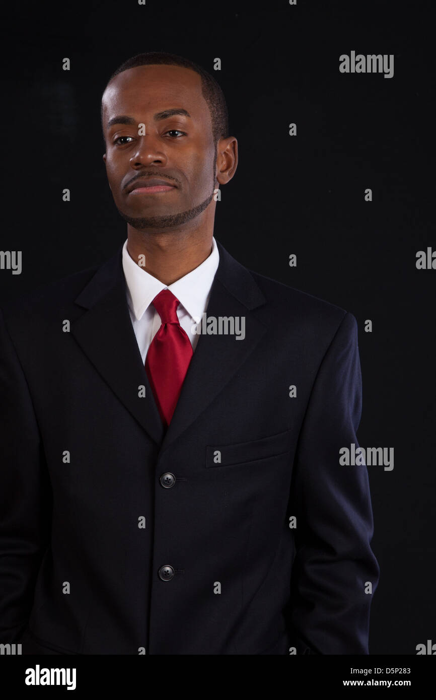 Black man in dark suit, white shirt and red tie, a successful, prosperous businessman, looking thoughtful Stock Photo